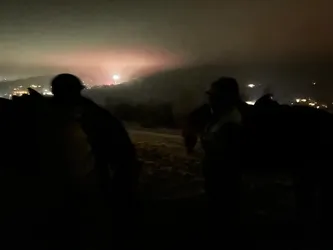 Menschen und Pferde als Silhouetten auf der Bergkuppe, in der Ferne Feuerwerk über den Tälern