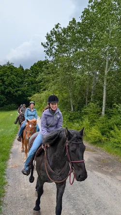 Zwei lachende Reiterinnen kommen auf dem Schotterweg entgegen, dahinter zwei weitere aus der Gruppe