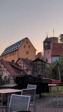 Blick über die Dächer von Schwarzenfels in der Abenddämmerung, dahinter Kirchturm und Burg