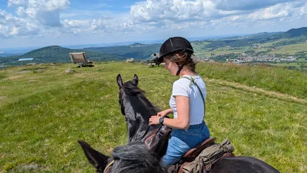 Reiterin schaut vom Gipfelplateau des Simmelsbergs über die Rhön, unten im Tal ein Ort