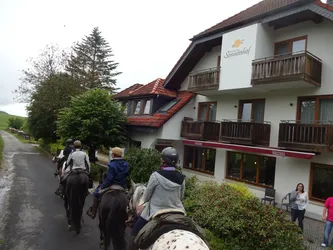 Die Gruppe reitet auf der Dorfstraße am Landgasthof Sonnenhof vorbei