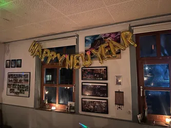 Goldene Ballonbuchstaben „Happy New Year“ über den Fenstern des Gastraums
