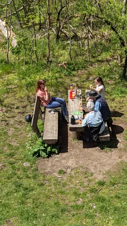 Die Gruppe macht Pause an den Picknickbänken am Waldrand