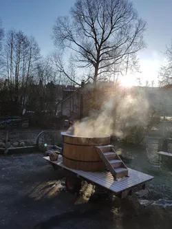 Dampf steigt aus dem hölzernen Hot Tub auf dem Anhänger, dahinter steht die tiefe Wintersonne