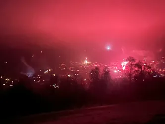 Feuerwerk färbt den Nachthimmel über dem Ort im Tal rot