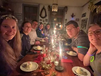 Die Gruppe beim Nachtisch an der Tafel, vor jedem ein Teller, dazwischen Kerzen und Knicklichter