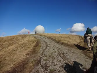 Der Schotterweg führt zum Radom auf dem Gipfel der Wasserkuppe hinauf, rechts zwei Reiter