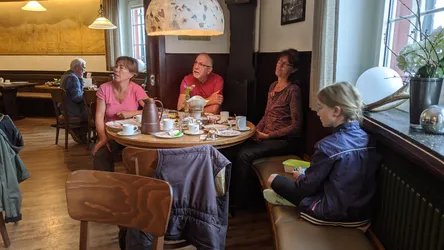 Die Gruppe frühstückt an einem runden Tisch in der Gaststube des Fuldaer Hauses