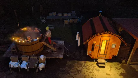 Blick von oben auf Hot Tub und Fasssauna im nächtlichen Hof