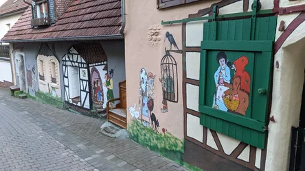 Bemalte Fensterläden und Wandbilder an einem Fachwerkhaus in der Ortsdurchfahrt
