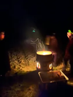Die Feuertonne brennt auf der Bergkuppe, ringsum stehen Menschen mit Knicklichtern