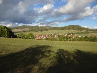 Weiter Blick über eine Wiese auf Seiferts im Tal, dahinter die bewaldeten Kuppen der Rhön