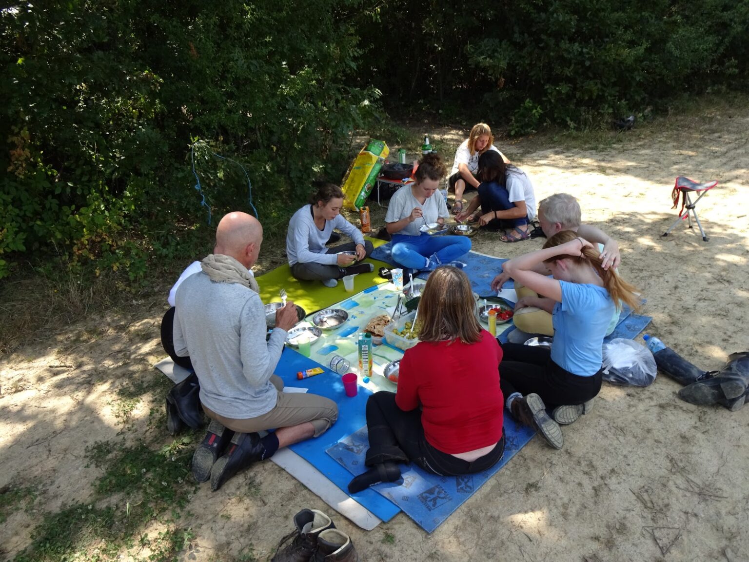 Mittagspause auf einer Picknickdecke im Schatten: die Reitgruppe sitzt um Brot und frisches Obst